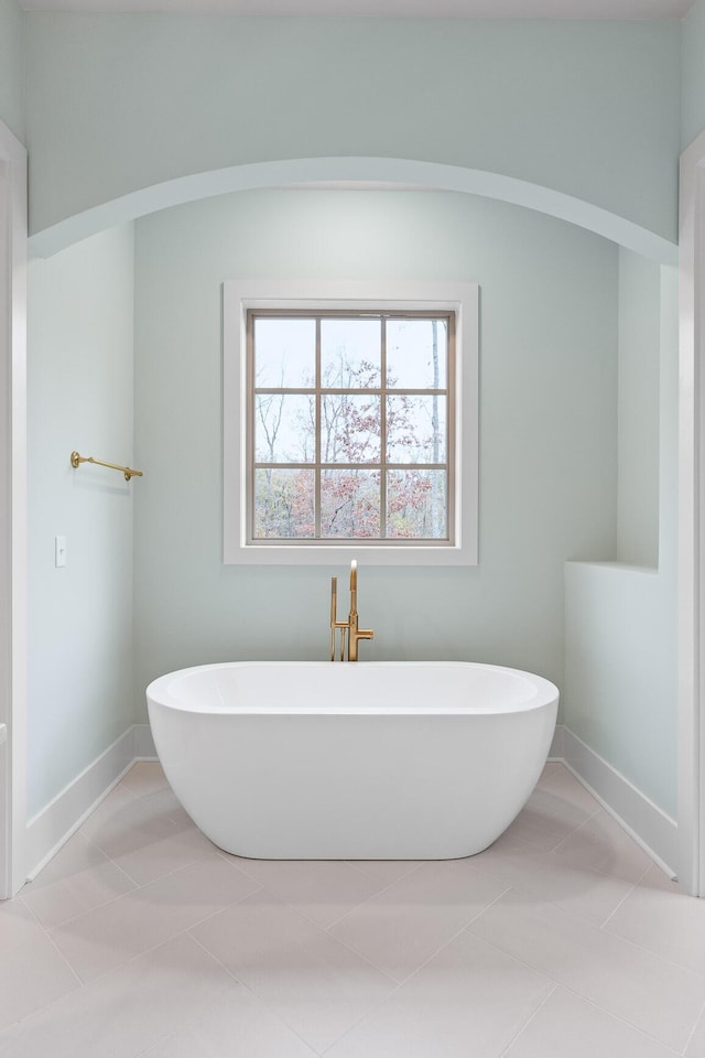 full bath with a soaking tub, tile patterned flooring, and baseboards