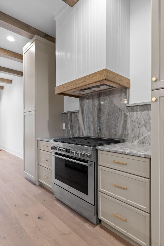kitchen featuring high end stainless steel range, custom range hood, backsplash, beam ceiling, and light wood-type flooring