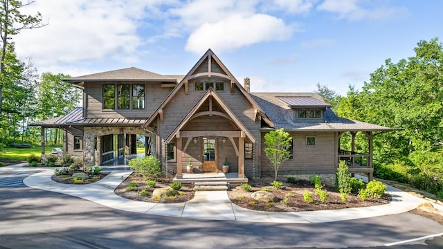 view of front of house with a standing seam roof, covered porch, metal roof, a chimney, and a shingled roof