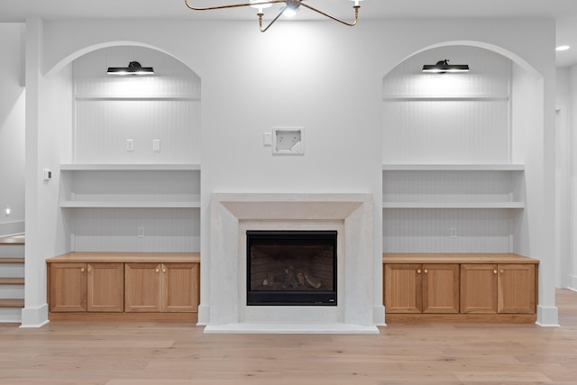 unfurnished living room featuring light wood-type flooring and a chandelier