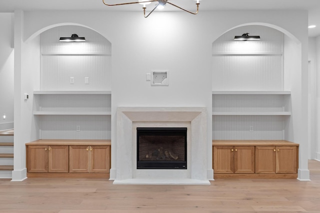 unfurnished living room featuring built in features, light wood-style floors, and a fireplace