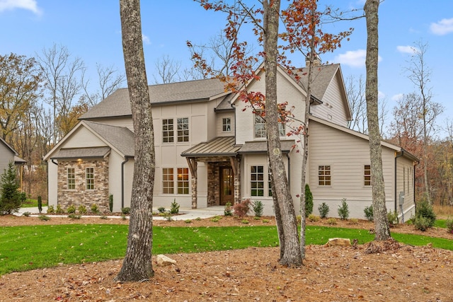 view of front of house with roof with shingles, stone siding, and a front lawn