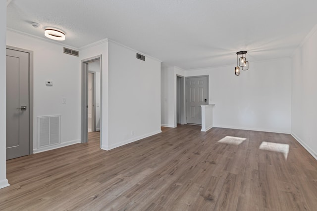 empty room featuring ornamental molding, wood-type flooring, and a textured ceiling