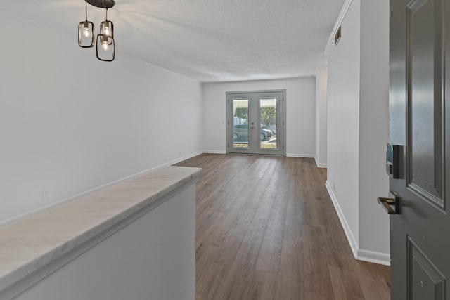 foyer with crown molding, dark hardwood / wood-style floors, a textured ceiling, and french doors