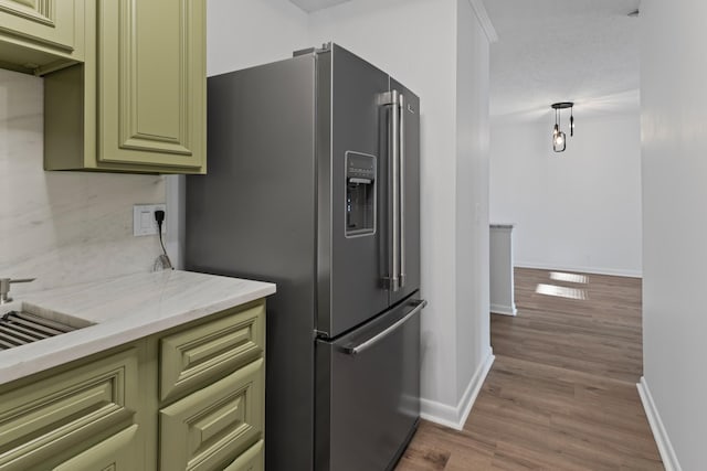 kitchen with pendant lighting, light stone counters, wood-type flooring, green cabinetry, and high end refrigerator