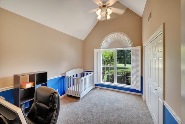 carpeted bedroom featuring high vaulted ceiling, ceiling fan, a nursery area, and a closet