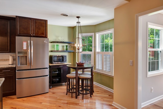 kitchen featuring light stone countertops, a wealth of natural light, pendant lighting, and appliances with stainless steel finishes