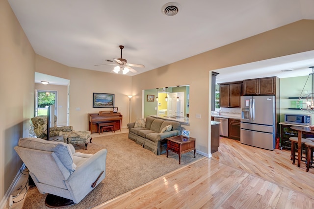 living room featuring ceiling fan, light hardwood / wood-style floors, and vaulted ceiling