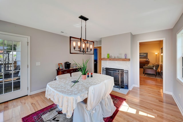 dining space featuring a notable chandelier, a premium fireplace, and light hardwood / wood-style flooring