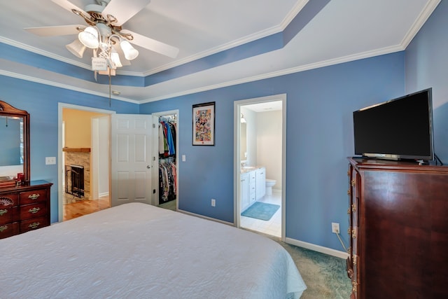 bedroom featuring light carpet, ceiling fan, a spacious closet, connected bathroom, and a closet