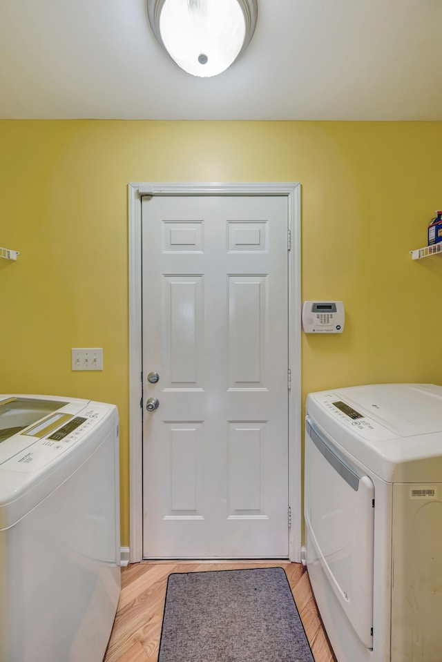 laundry area with light hardwood / wood-style flooring and washer and dryer