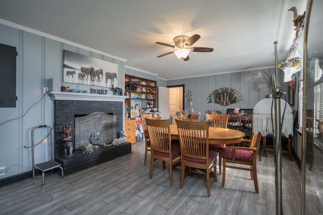 dining area with a fireplace, ceiling fan, hardwood / wood-style floors, and ornamental molding