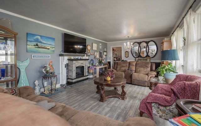 living room with hardwood / wood-style floors, an inviting chandelier, a stone fireplace, and crown molding