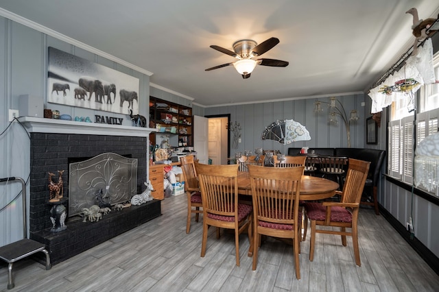 dining area with a fireplace, hardwood / wood-style flooring, ceiling fan, and crown molding