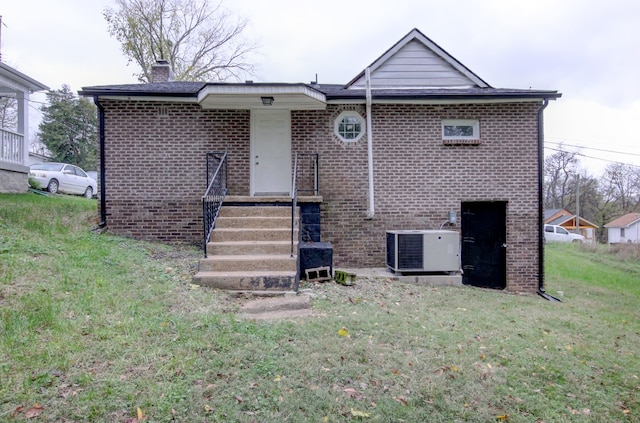 rear view of property with a lawn and central air condition unit