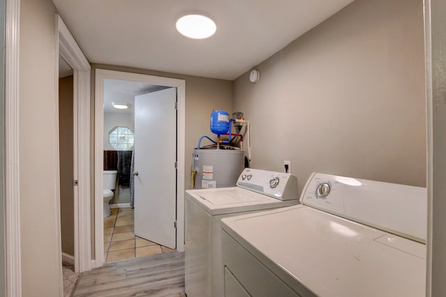 clothes washing area featuring light wood-type flooring, washer and dryer, and water heater