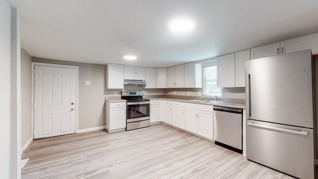 kitchen featuring sink, white cabinets, light wood-type flooring, and appliances with stainless steel finishes