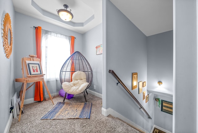 sitting room with a tray ceiling and carpet floors