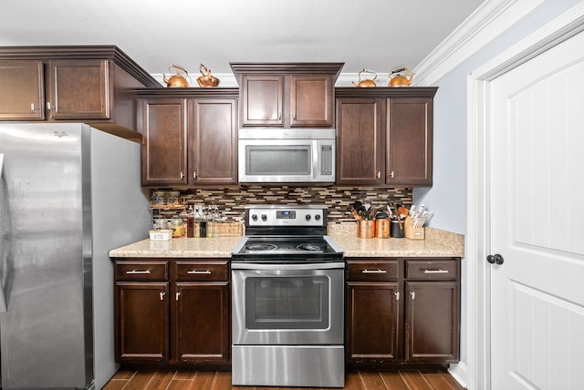 kitchen featuring appliances with stainless steel finishes, hardwood / wood-style flooring, tasteful backsplash, and crown molding