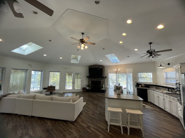 living room featuring a stone fireplace, a wealth of natural light, and dark wood-type flooring