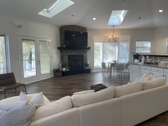 living room featuring dark wood-type flooring, vaulted ceiling with skylight, a healthy amount of sunlight, and an inviting chandelier