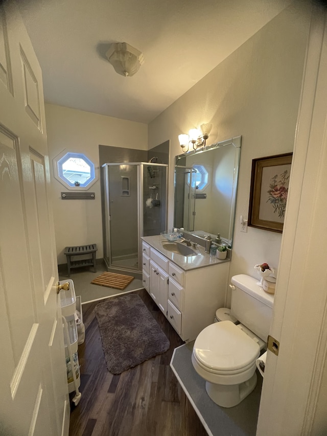 bathroom featuring vanity, wood-type flooring, a shower with shower door, and toilet