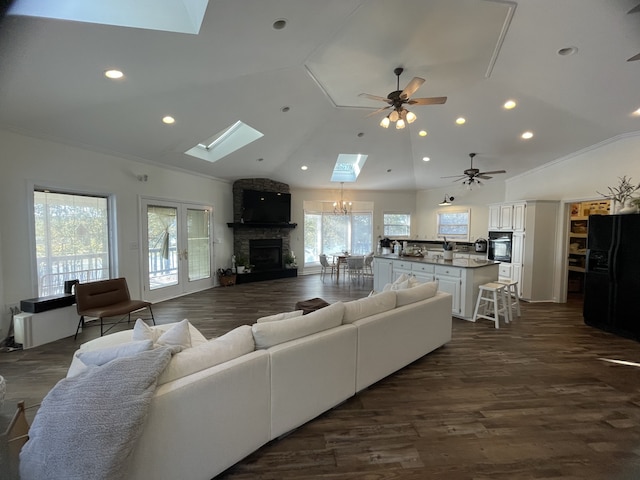 living room with vaulted ceiling with skylight, a healthy amount of sunlight, and dark hardwood / wood-style flooring