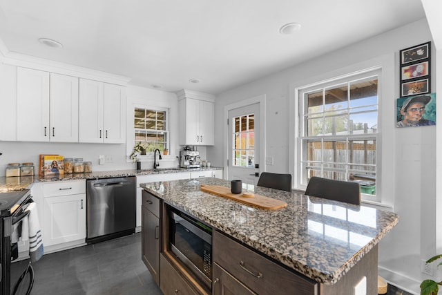 kitchen with a center island, white cabinets, a healthy amount of sunlight, and appliances with stainless steel finishes