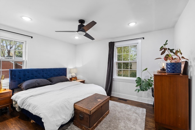 bedroom featuring dark hardwood / wood-style flooring, multiple windows, and ceiling fan