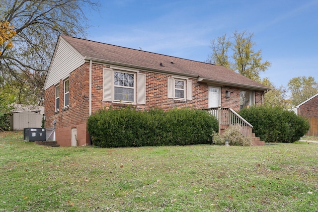 ranch-style home featuring a front yard and a storage unit