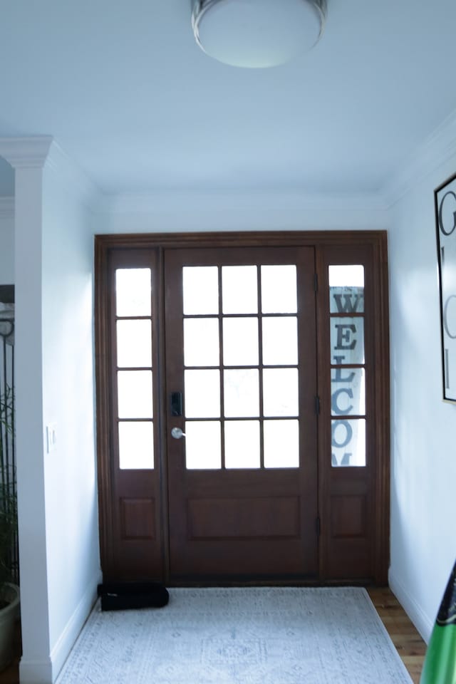 doorway featuring light wood-type flooring and crown molding