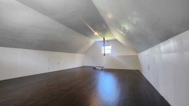 bonus room with dark hardwood / wood-style flooring and vaulted ceiling