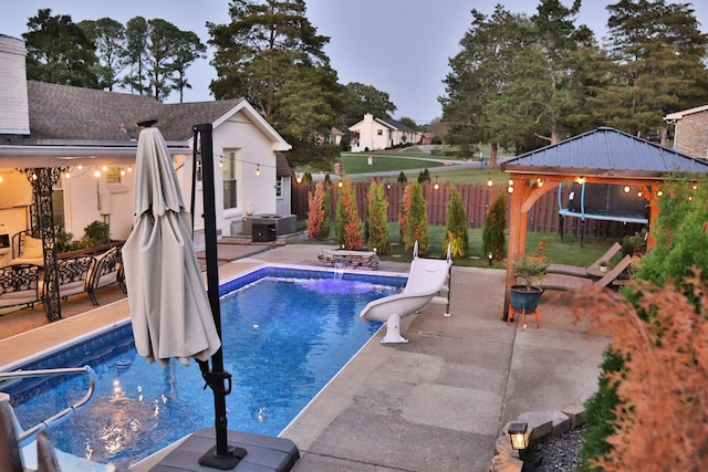 pool at dusk with a patio and a trampoline