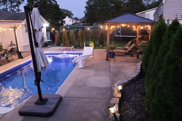 view of swimming pool featuring a gazebo, a patio, a trampoline, and a water slide