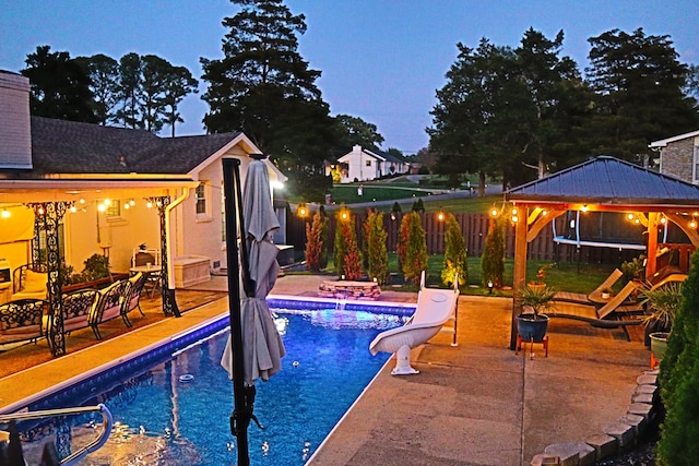 pool at dusk featuring a gazebo, a water slide, and a patio