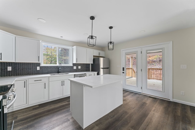 kitchen featuring white cabinets, decorative light fixtures, stainless steel appliances, and a healthy amount of sunlight