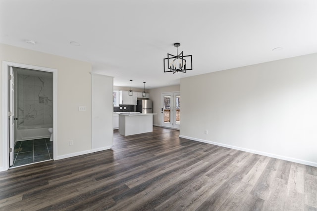 unfurnished living room with dark hardwood / wood-style floors and an inviting chandelier