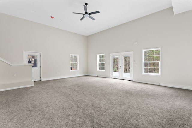 unfurnished living room with carpet floors, ceiling fan, french doors, and high vaulted ceiling