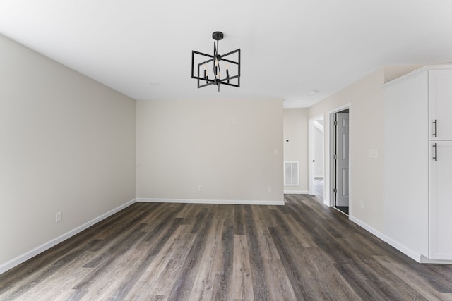 empty room featuring dark hardwood / wood-style floors and a notable chandelier