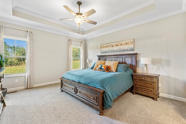 carpeted bedroom with a tray ceiling, ceiling fan, and ornamental molding