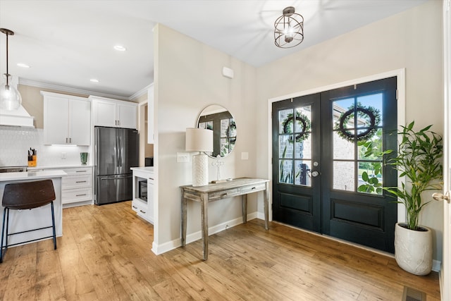 entryway with french doors, light hardwood / wood-style flooring, and crown molding