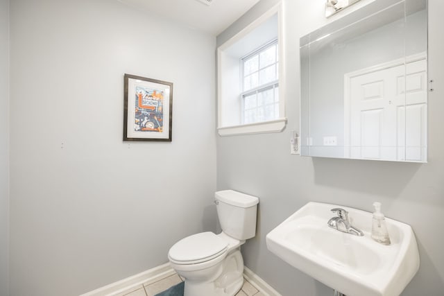 bathroom with toilet, sink, and tile patterned flooring