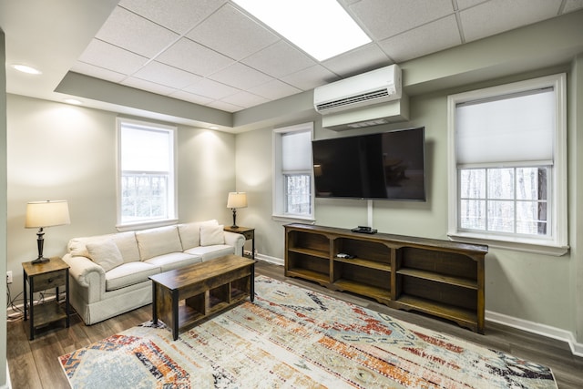 living room with hardwood / wood-style flooring, a drop ceiling, and a wall mounted AC