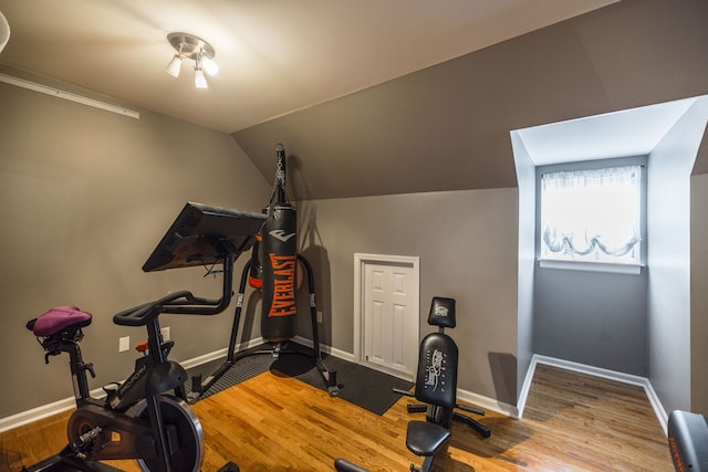 workout area featuring light wood-type flooring and lofted ceiling