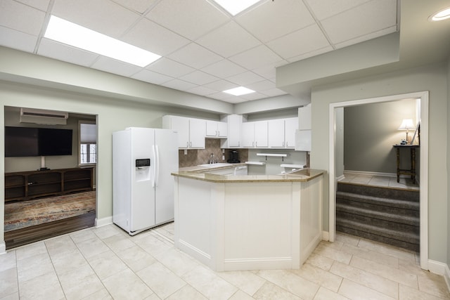 kitchen featuring kitchen peninsula, white cabinetry, white fridge with ice dispenser, and light tile patterned flooring