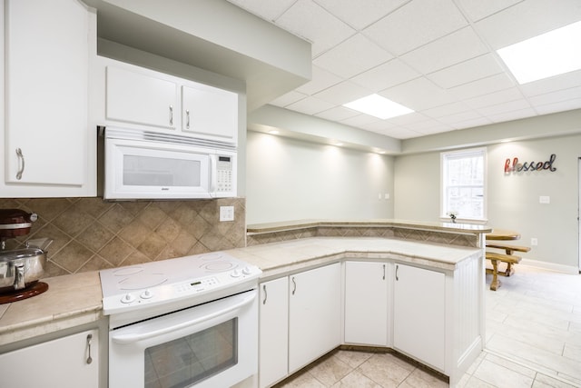 kitchen featuring white cabinets, white appliances, kitchen peninsula, and backsplash