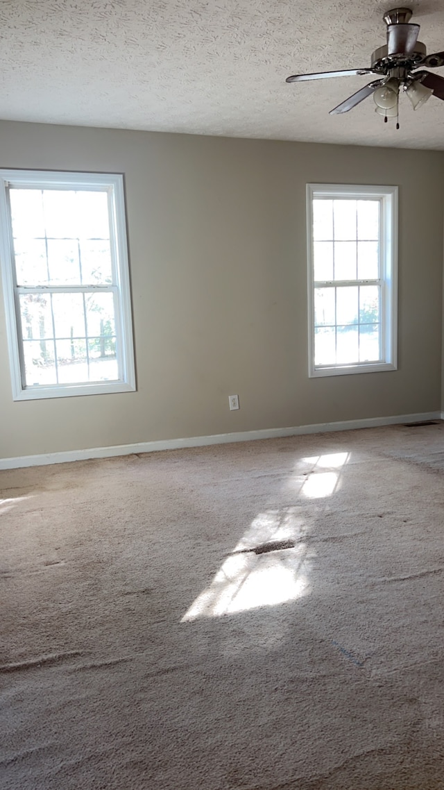 spare room featuring carpet flooring, ceiling fan, and a textured ceiling