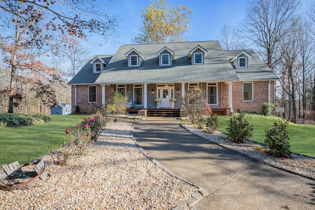 cape cod home featuring a shed, a front lawn, and a porch