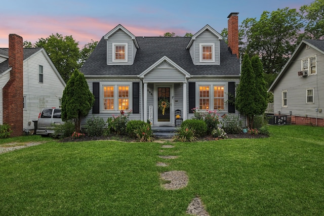 cape cod home with a yard and cooling unit