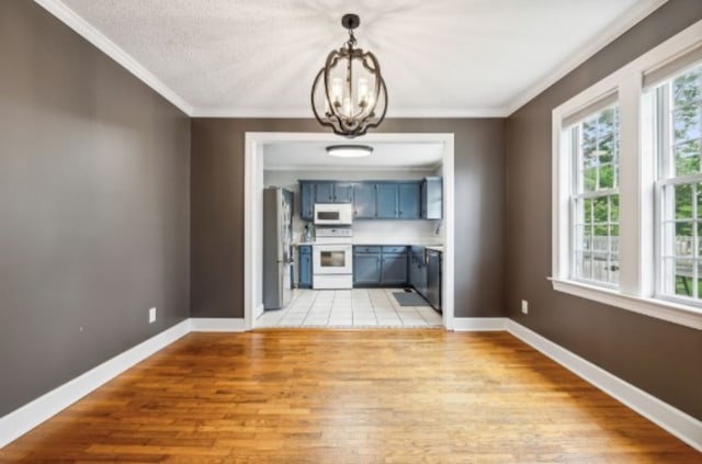 unfurnished living room featuring a notable chandelier, light wood-type flooring, and ornamental molding